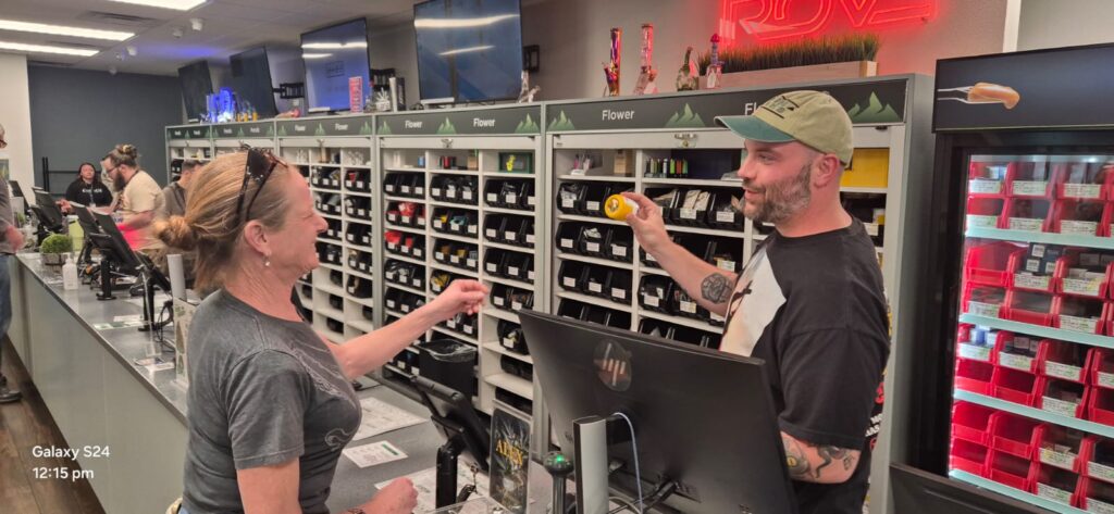Interior of The Dispensary in Nevada, featuring knowledgeable staff assisting customers and a well-organized display of a wide variety of lab-tested cannabis products, reflecting a focus on quality, education, and exceptional service.