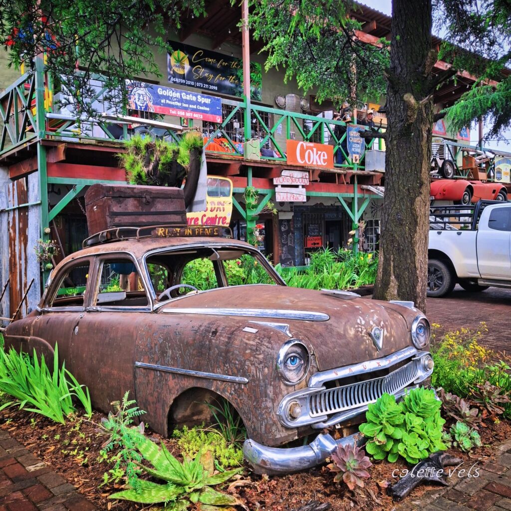 A vintage antique car repurposed into a vibrant art piece standing outside the Voetstoots Centre in Clarens.